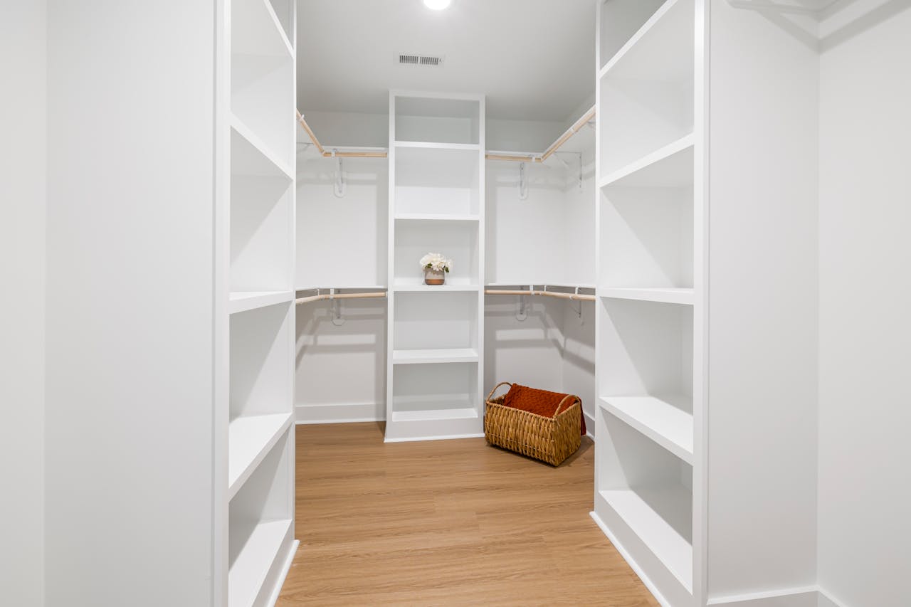 heros-img Modern walk-in closet with wooden floor and white shelves, perfect for storage.